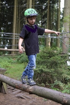 Child balancing on log shows confidence in the face of risk.