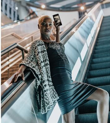 woman holding cell phone as she goes up the escalator